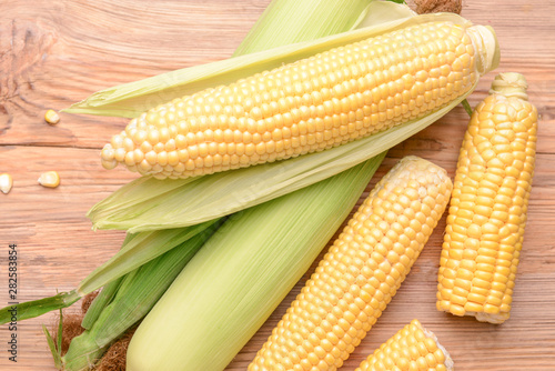 Fresh corn cobs on wooden background