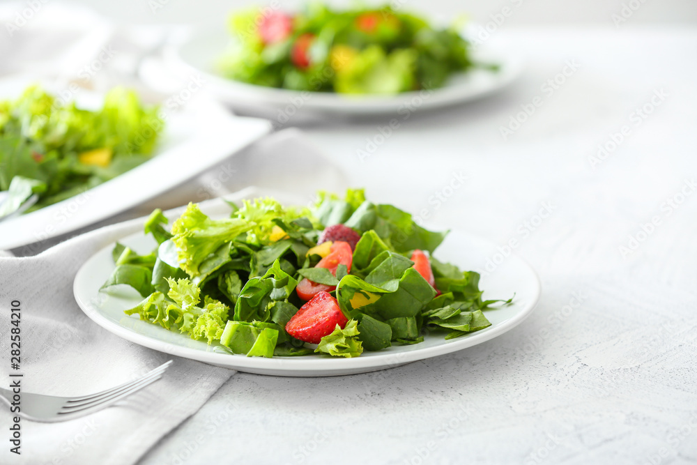 Plates with fresh tasty salad on light table Plates with fresh tasty salad on light table
