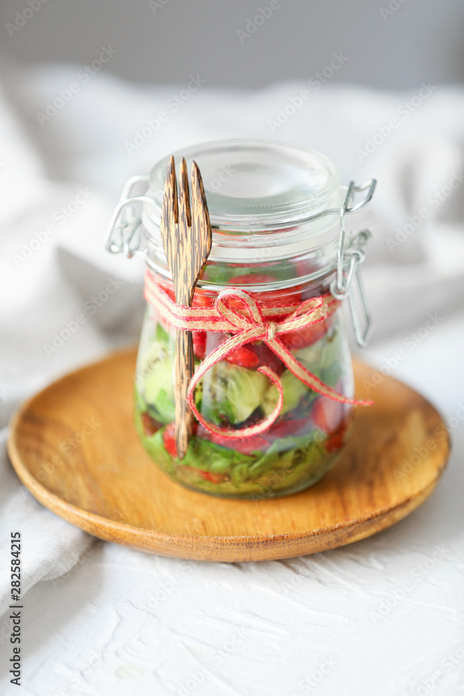 Glass jar with fresh tasty salad on table Glass jar with fresh tasty salad on table
