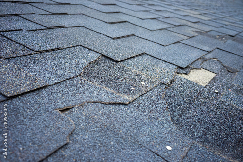 Close up view of bitumen shingles roof damage that needs repair. - obrazy, fototapety, plakaty 