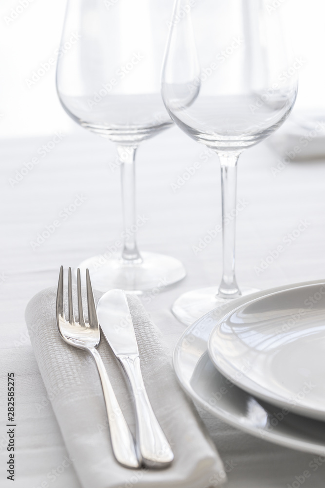 Table setting with white plates, silver cutlery and glasses for elegant festive dinner. Dinning concept background. Table setting with white plates, silver cutlery and glasses for elegant festive dinner. Dinning concept background.