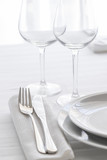 Table setting with white plates, silver cutlery and glasses for elegant festive dinner. Dinning concept background.