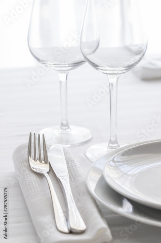 Table setting with white plates, silver cutlery and glasses for elegant festive dinner. Dinning concept background.