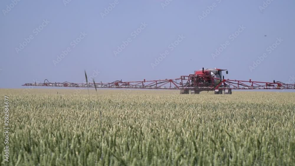 Massive self propelled sprayer with long arm is driving through the field Massive self propelled sprayer with long arm is driving through the field
