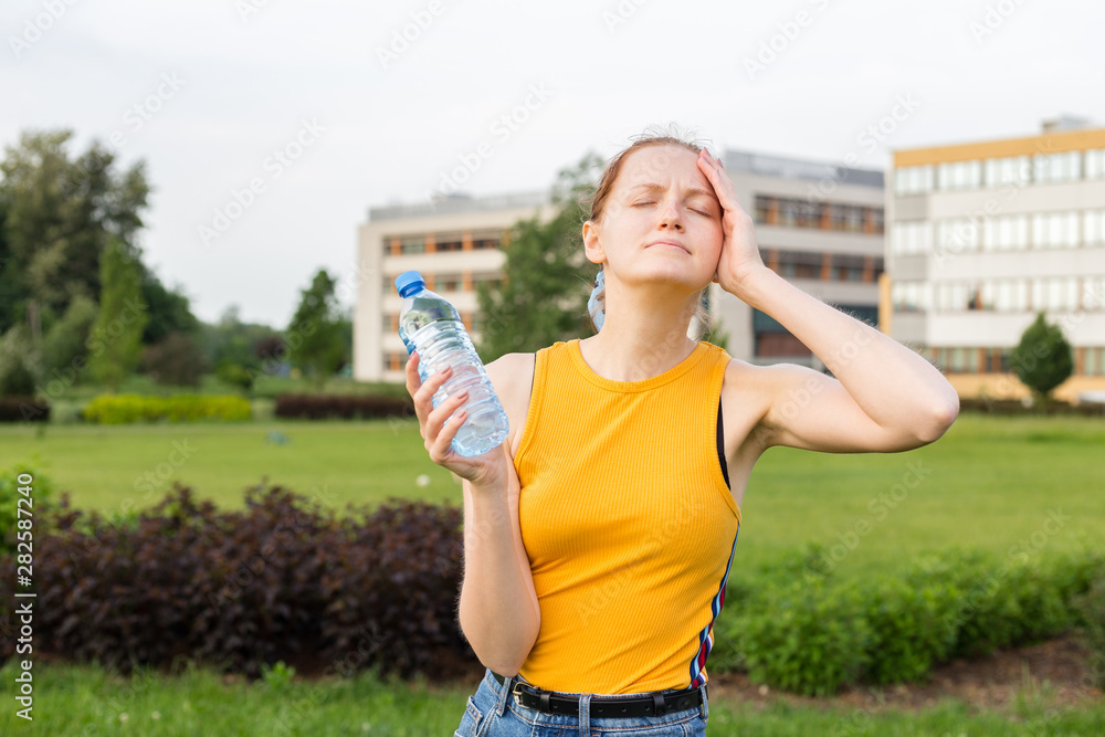 Woman holding water bottle stressed with hand on head, shocked with shame and surprise face, angry and frustrated. Presenting your product. Emotional, young face.