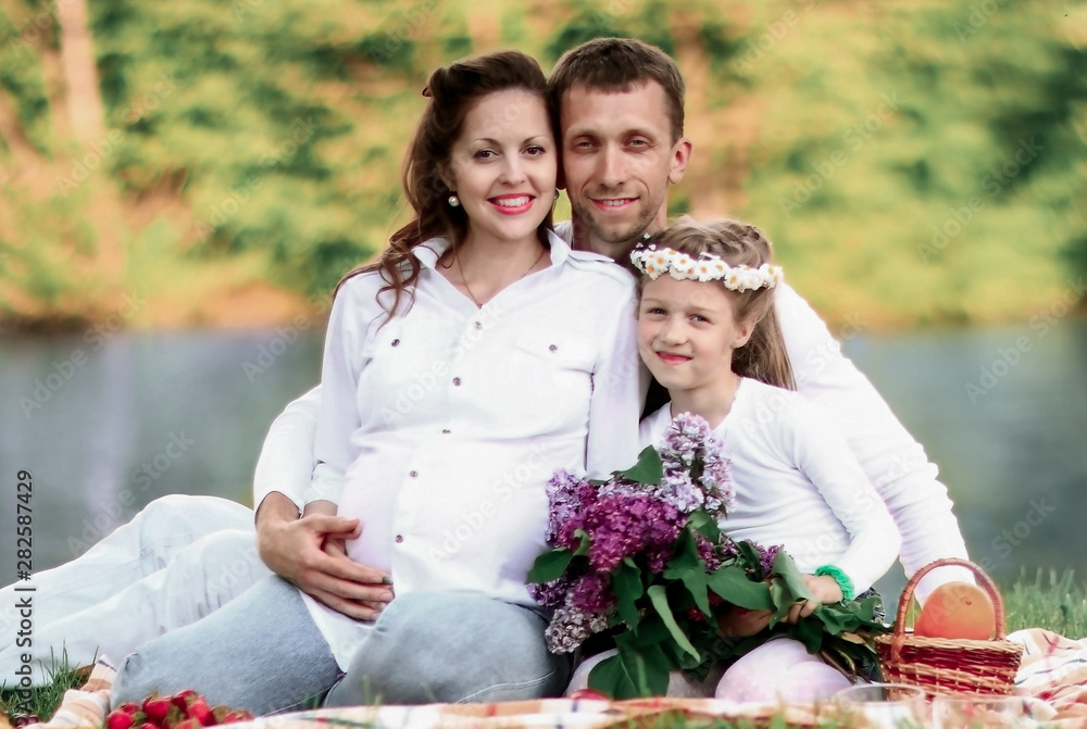 happy father of a daughter and a pregnant mom at a picnic. happy father of a daughter and a pregnant mom at a picnic.