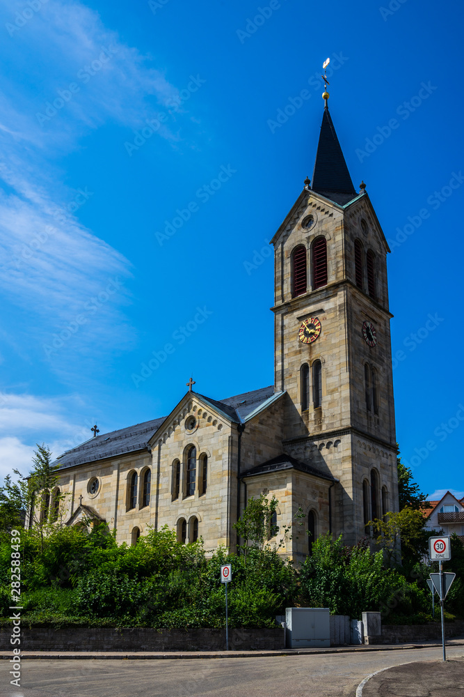 Germany, Historical church building in kaisersbach near welzheim decorated by green trees under blue sky in summer