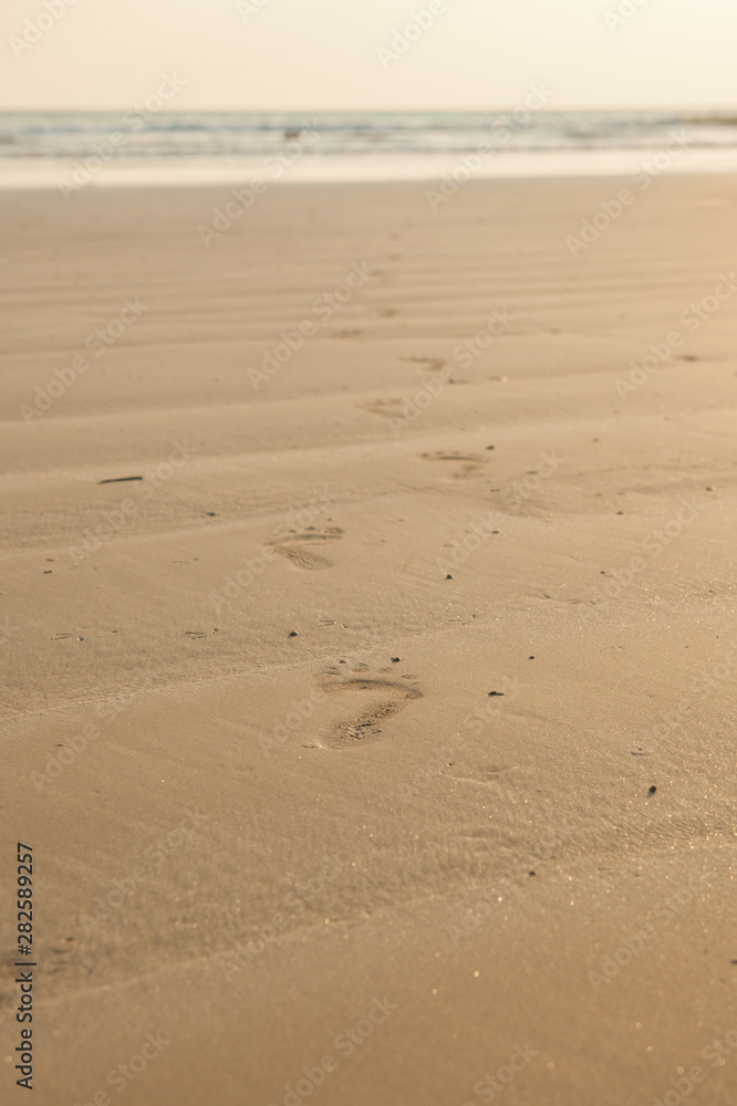 close up of footprints on the beach with golden sand close up of footprints on the beach with golden sand