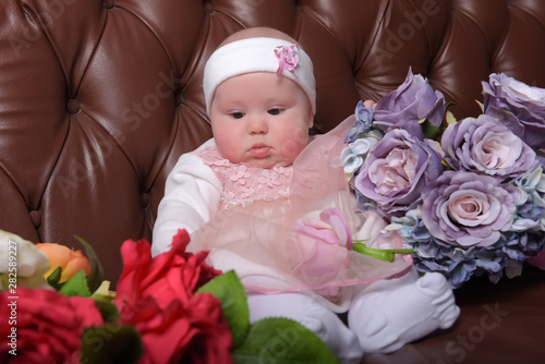 girl five months in a pink dress with bouquets of flowers photo