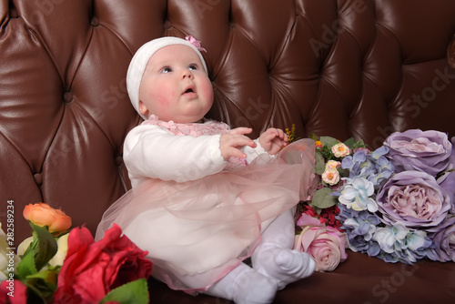 girl five months in a pink dress with bouquets of flowers photo