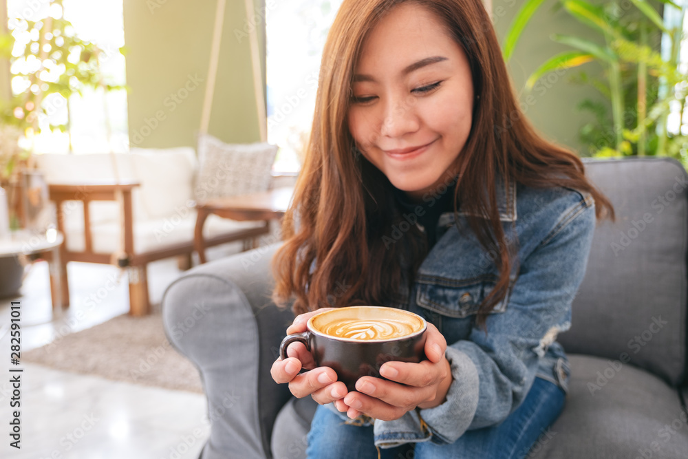 Closeup image of a beautiful asian woman holding and drinking hot coffee in cafe Closeup image of a beautiful asian woman holding and drinking hot coffee in cafe