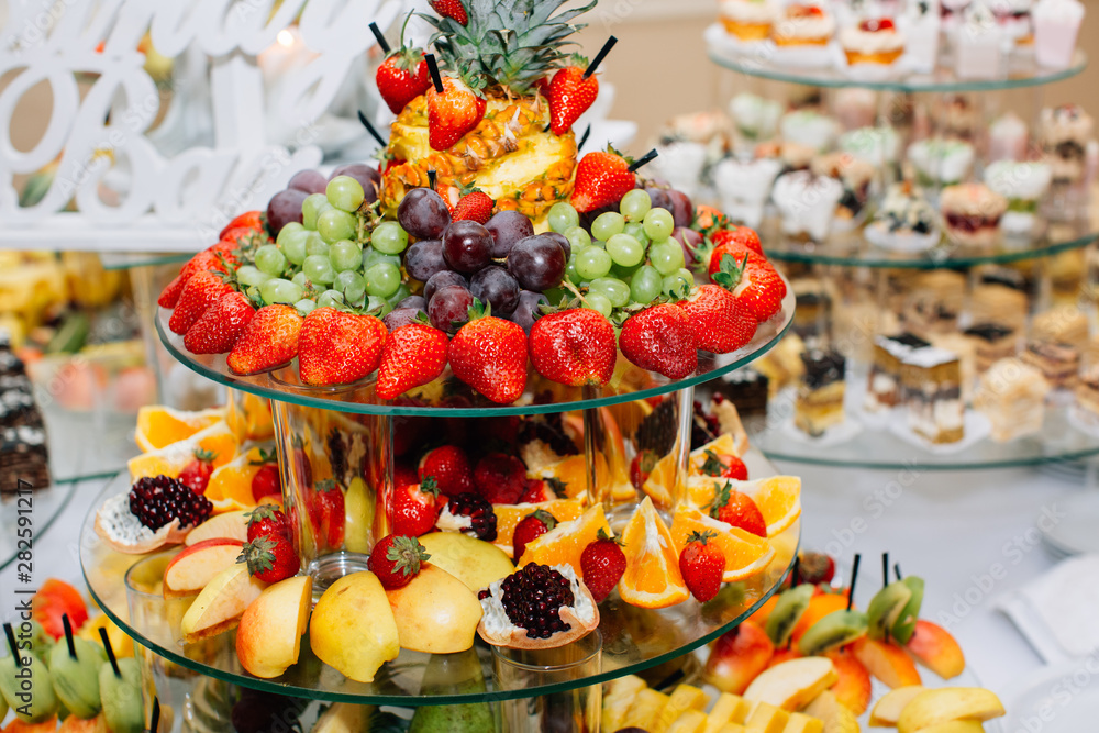 Wedding reception catering table with different fruits and cakes