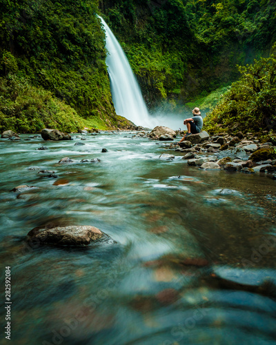 Fototapeta Naklejka Na Ścianę i Meble -  Person watching a beautiful waterfall in Ecuador