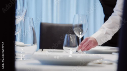 The waiter is serving a table in the restaurant. Someone is setting the table in an Italian restaurant. Plates fork glasses put on the table. food video close up