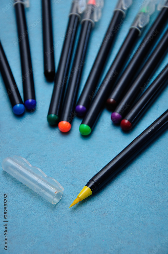 A yellow color pen with the rest out of focus on a blue background A yellow color pen with the rest out of focus on a blue background