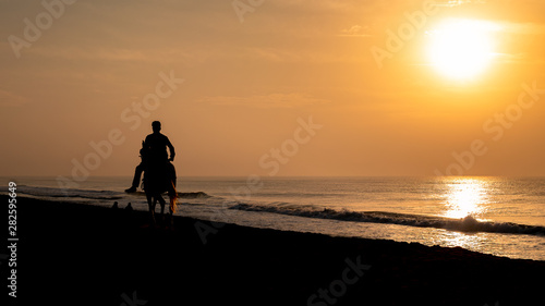Silhouette of horse with its owner at the beach of Puri,India.