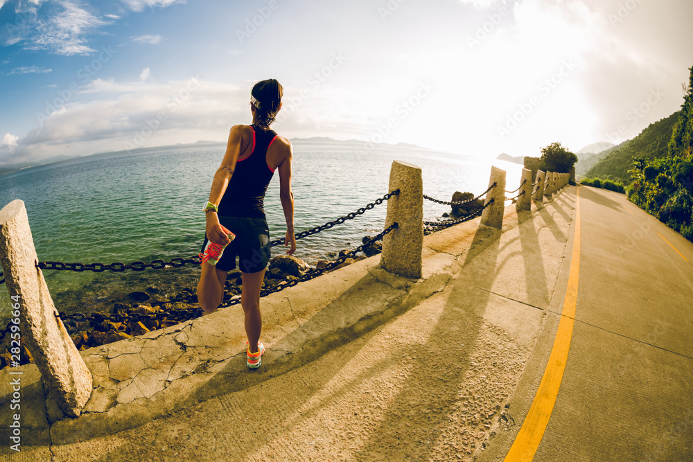 Fitness woman warming up on seaside trail in the morning