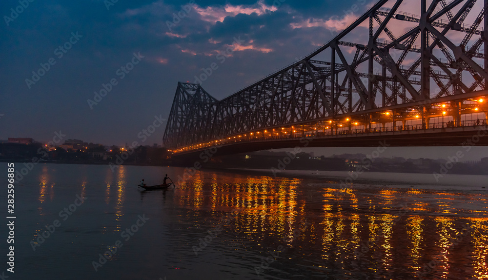 Silhouette of Howrah Bridge at the time of Sunrise.  Howrah Bridge is a bridge with a suspended span over the Hooghly River in West Bengal.