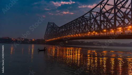 Silhouette of Howrah Bridge at the time of Sunrise.  Howrah Bridge is a bridge with a suspended span over the Hooghly River in West Bengal. photo
