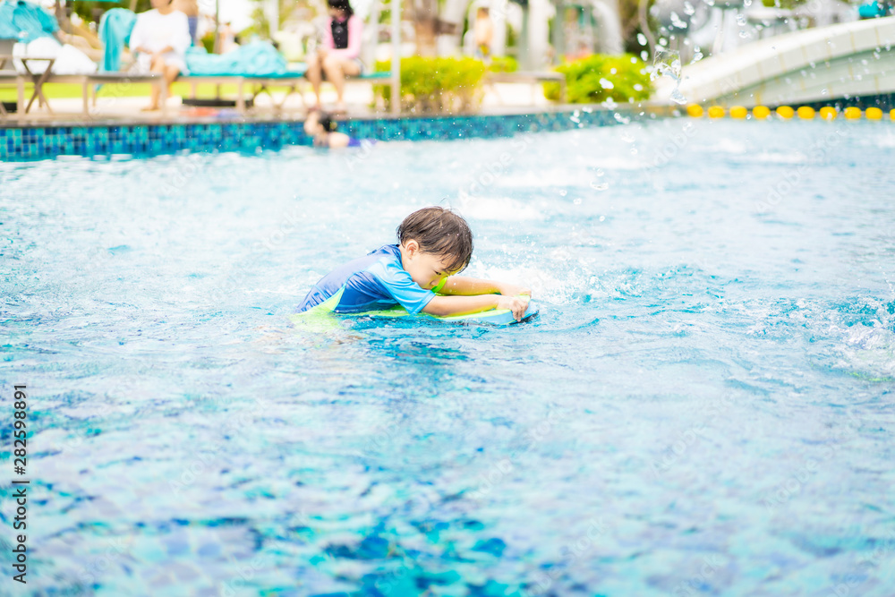 A boy is playing and swimming at the swimming pool in the evening.
