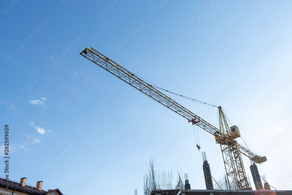 Tower crane on the blue sky background. Building construction work concept, investments in the development construction buildings and structures industry. Tower crane on the blue sky background. Building construction work concept, investments in the development construction buildings and structures industry.