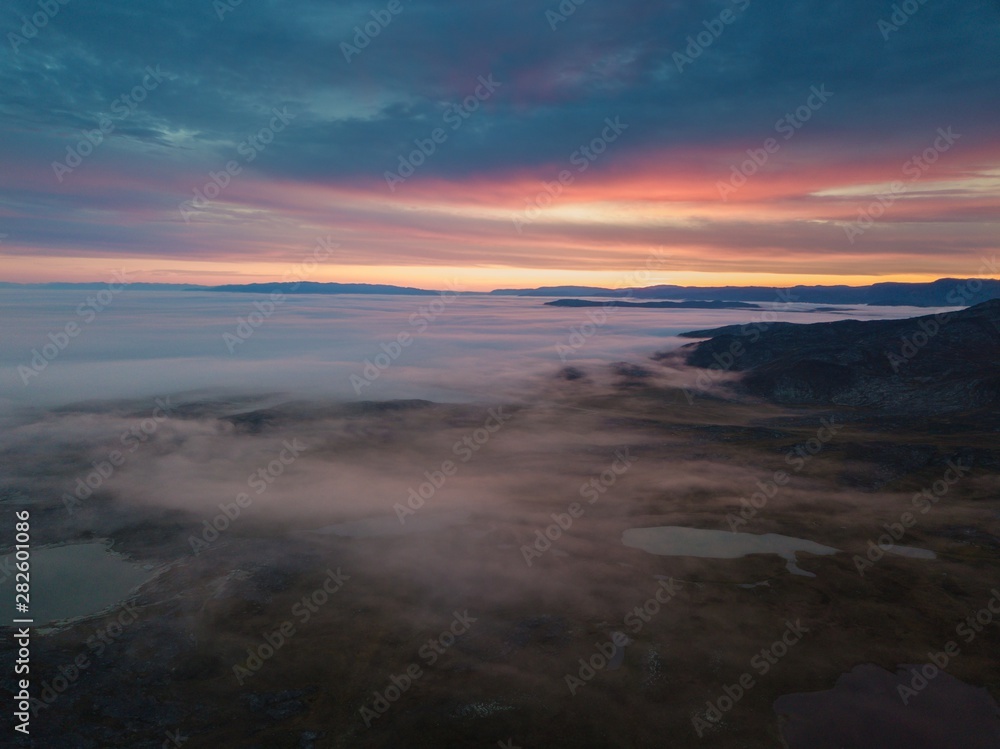 Misty morning in Greenland. Colorful landscape winh lakes, mountains and fog. Aerianl drone view.