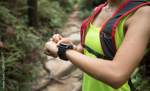 Asian woman ultramarathon runner set the smartwatch before running at tropical rainforest trail