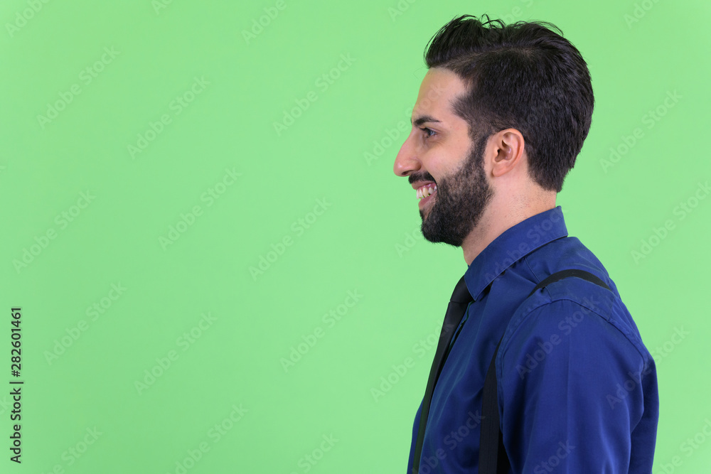 Closeup profile view of young happy bearded Persian businessman smiling Closeup profile view of young happy bearded Persian businessman smiling