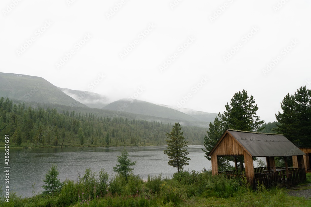 Fototapeta premium low clouds and fog over the lake in the mountains with wooden house