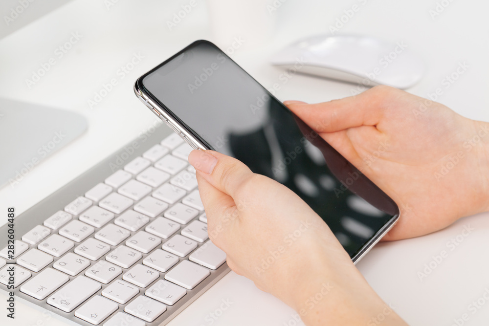 Close up of female hands using smartphone at office table