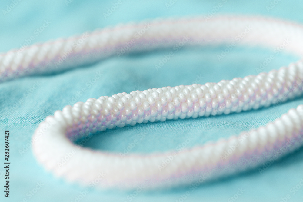 White beaded necklace on a blue textile background close up White beaded necklace on a blue textile background close up