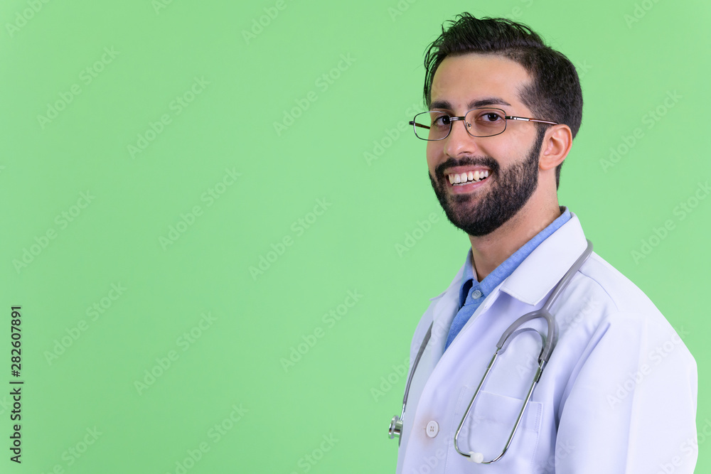 Closeup profile view of happy young bearded Persian man doctor looking at camera Closeup profile view of happy young bearded Persian man doctor looking at camera
