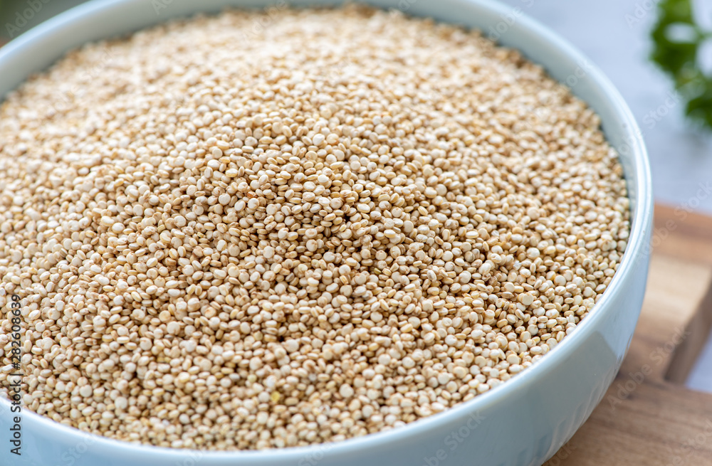 Dry white quinoa seeds in a bowl. Healthy vegetarian food, gluten free, balanced diet concept.