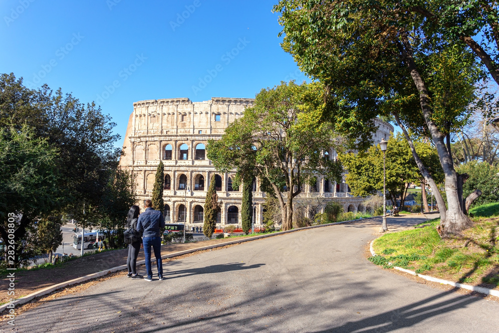 The girl and the guy in the park, looking at the Colosseum in Rome.