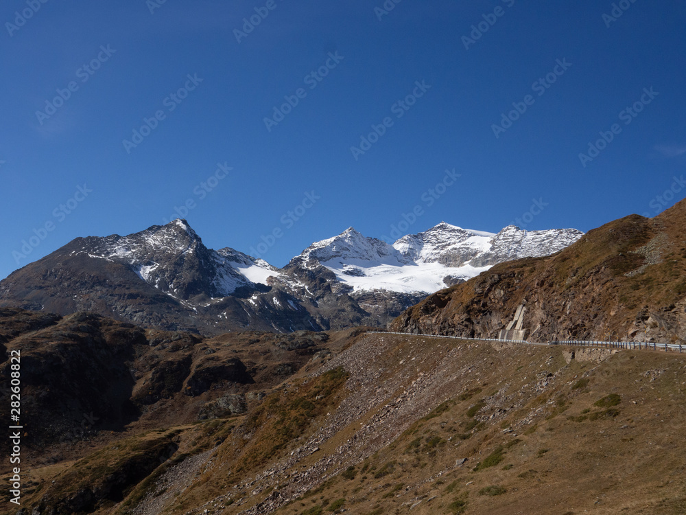 Road going up the Passeo del Bermina, Switzerland, with snowy peaks and sparse vegetation