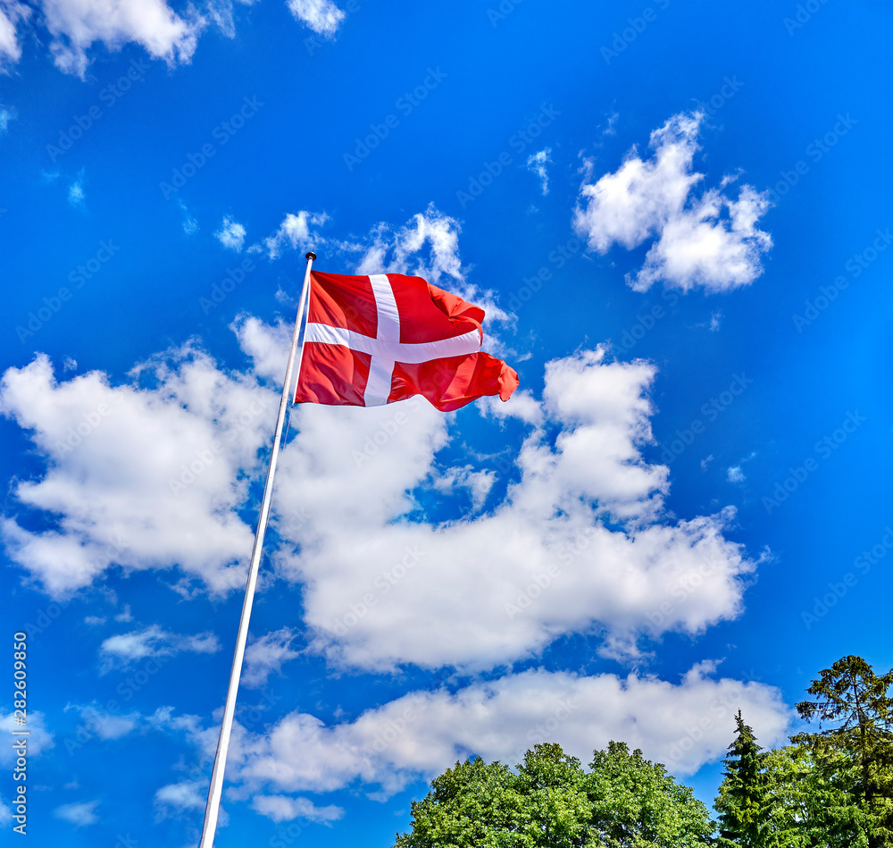 denmark flag in the wind with blue sky and clouds.