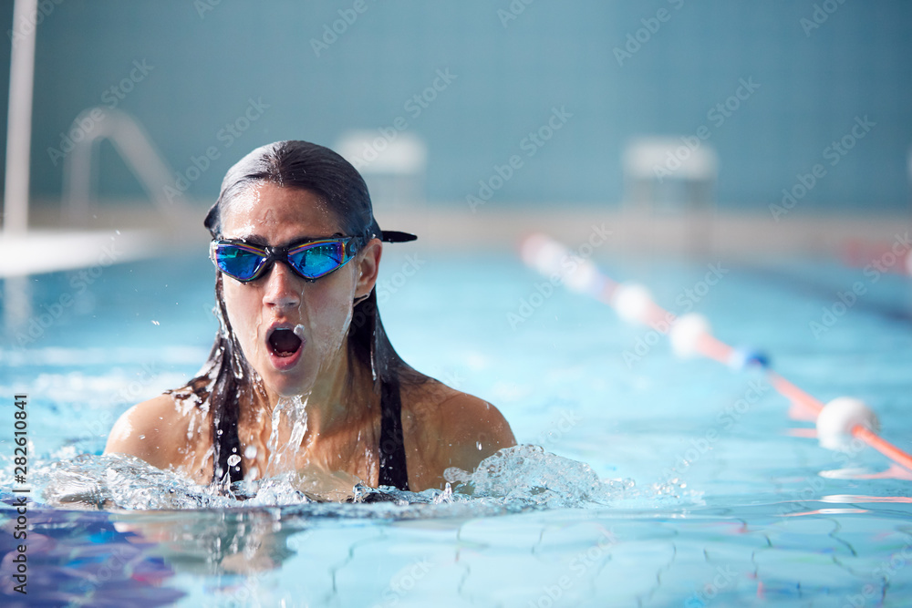 Female Swimmer Wearing Goggles Training In Swimming Pool