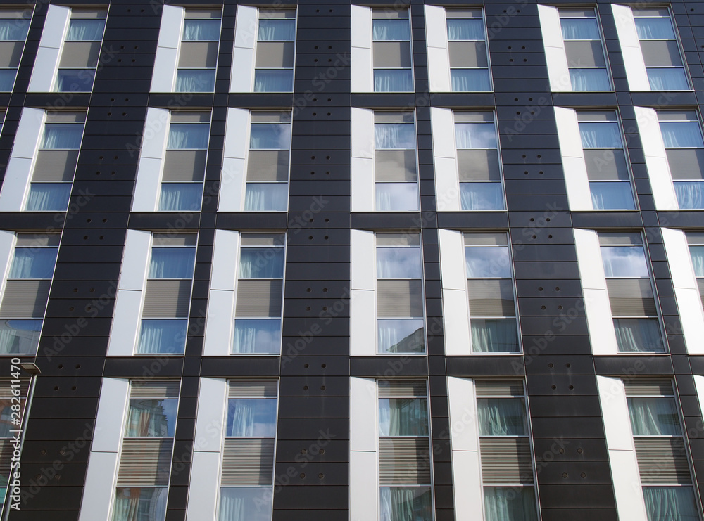 view of the facade of a large black and white modern commercial building with repeating windows and geometric panels view of the facade of a large black and white modern commercial building with repeating windows and geometric panels