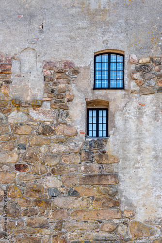 Vertical frame of two windows on an old rough acient medieval stone wall at Varberg Fortress in Sweden.