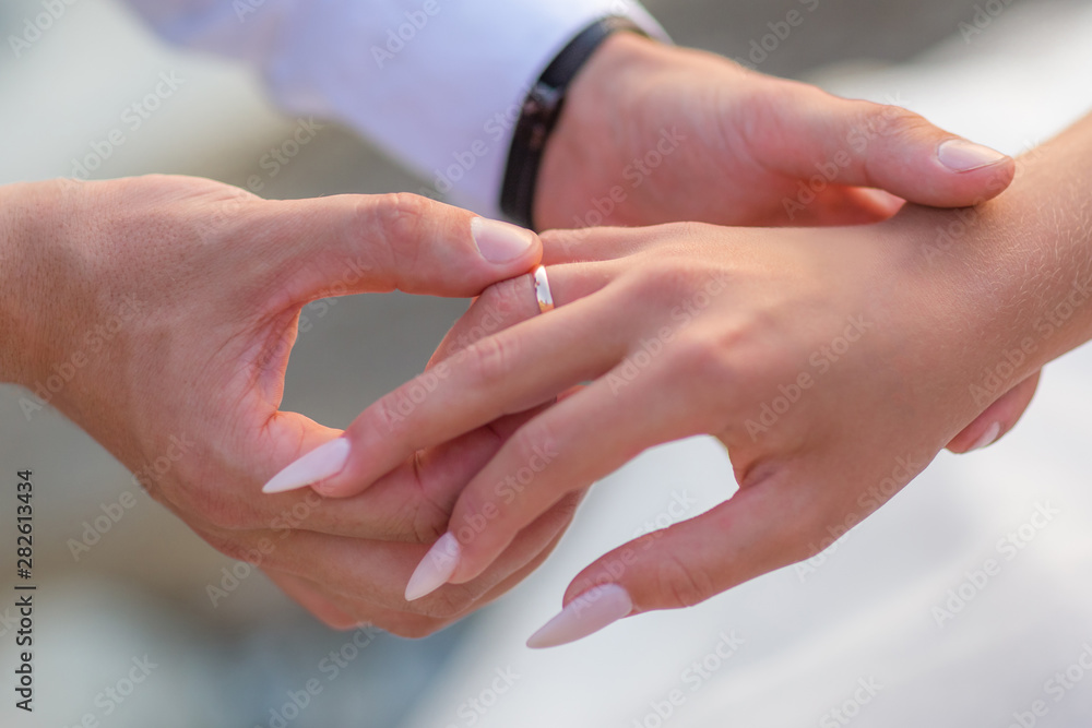 Groom slipping ring on finger of bride at wedding Groom slipping ring on finger of bride at wedding