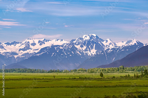 pastoral panorama of the chugach mountains and forest southeast of anchorage alaska with green meadows in the foreground