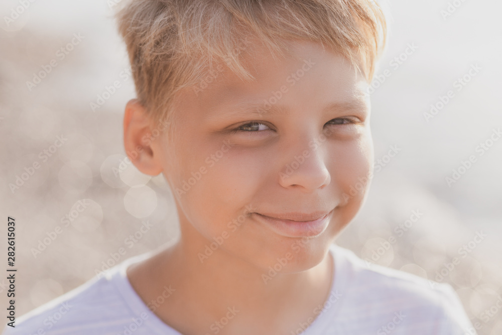 Closeup portrait of smiling happy handsome boy standing at summer sunny beach in morning and looking at camera happily. Horizontal color photography. Closeup portrait of smiling happy handsome boy standing at summer sunny beach in morning and looking at camera happily. Horizontal color photography.