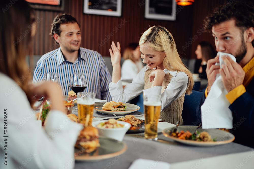 Multiethnic friends sitting at restaurant, drinking alcohol, chatting and having burgers for dinner. Multiethnic friends sitting at restaurant, drinking alcohol, chatting and having burgers for dinner.