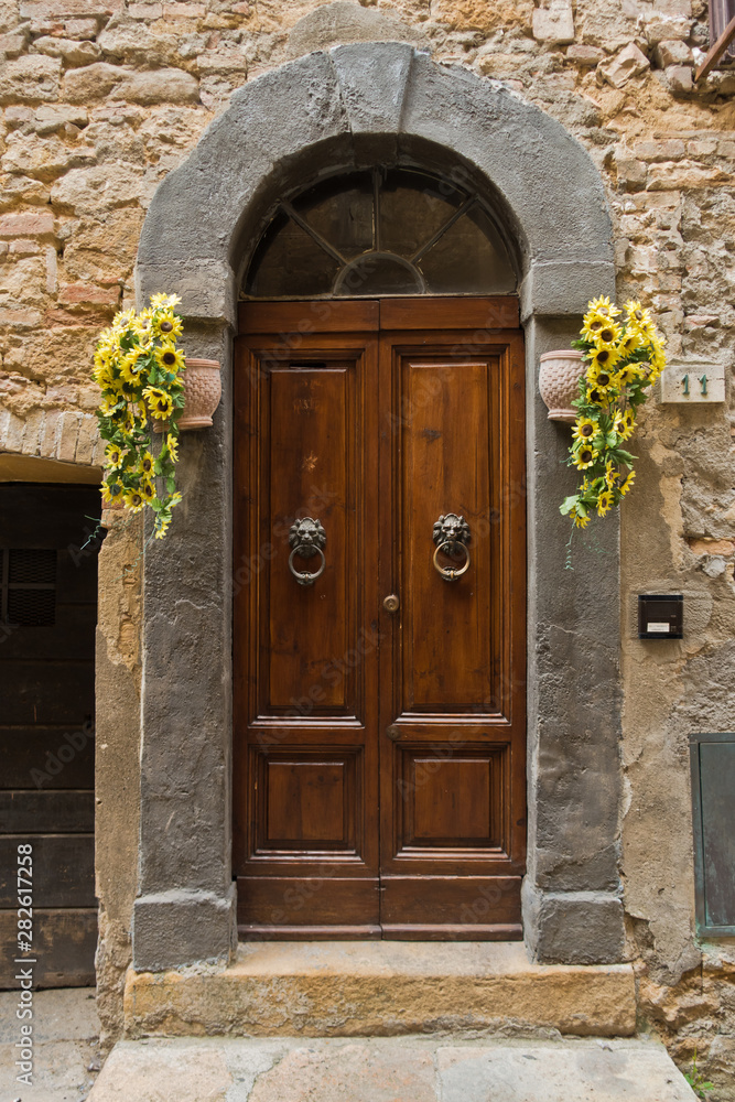 Sunflowers by the door at narrow winding street in city Voltera, Tuscany, Italy Sunflowers by the door at narrow winding street in city Voltera, Tuscany, Italy