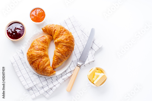 Top view flatlay with fresh croissants served with jams and buter. Morning meal concept. White background photo