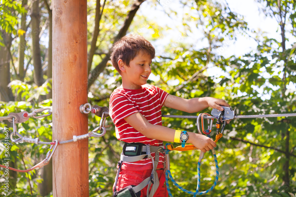 Obraz premium Happy boy learn to use zip line trolley, rope park