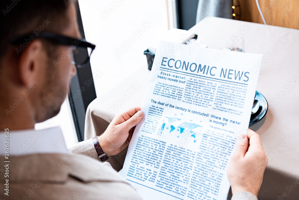 cropped view of businessman reading newspaper in cafe cropped view of businessman reading newspaper in cafe