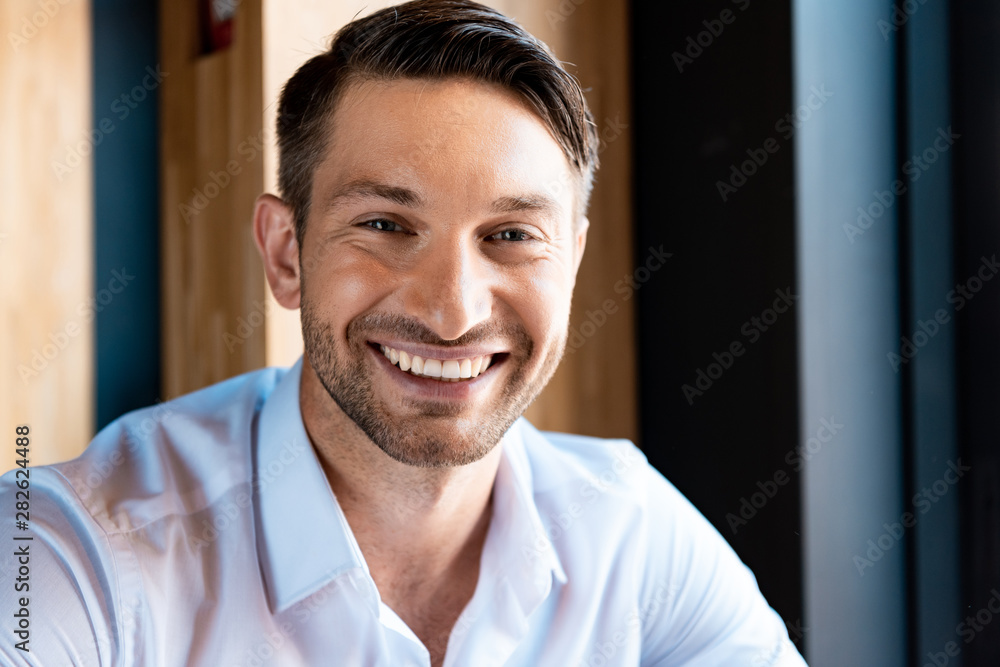 front view of smiling handsome man looking at camera in cafe front view of smiling handsome man looking at camera in cafe