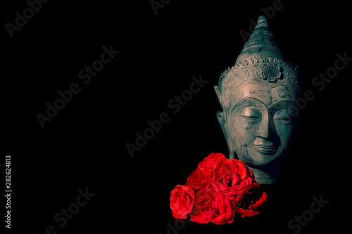 Peace and love. Traditional meditating Buddha head with red roses photo