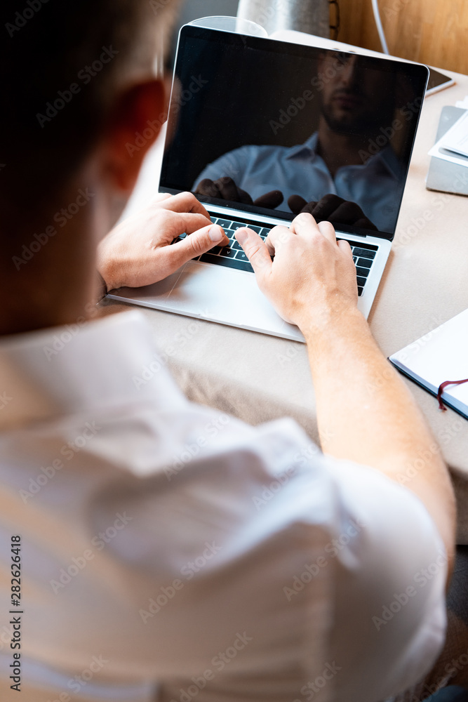 Obraz premium cropped view of man typing on laptop keyboard in cafe